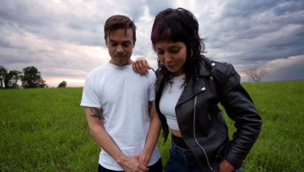 Sleigh Bells | Texis Sleigh Bells band photo. Indie music album review, September 2021. Duo in field with cloudy sky.