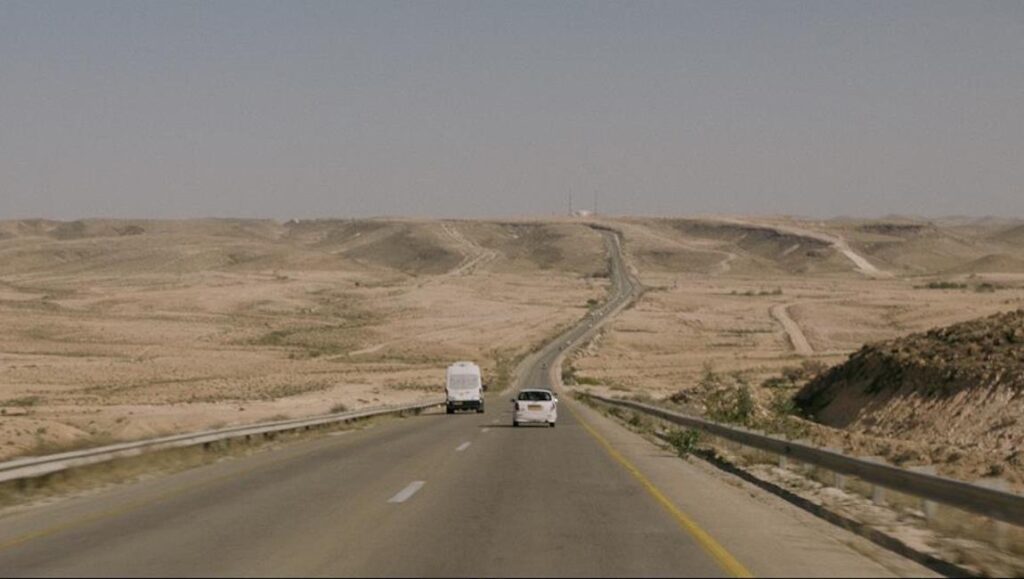 The Forgotten Ones DOC NYC 2021 film still. Desert highway with two vehicles.