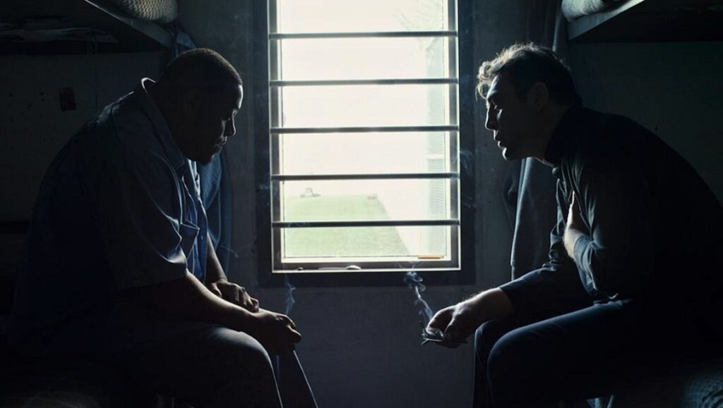 Thy Kingdom Come | Eugene Richards Eugene Richards' Thy Kingdom Come shows two men smoking by a barred window in a dark room.