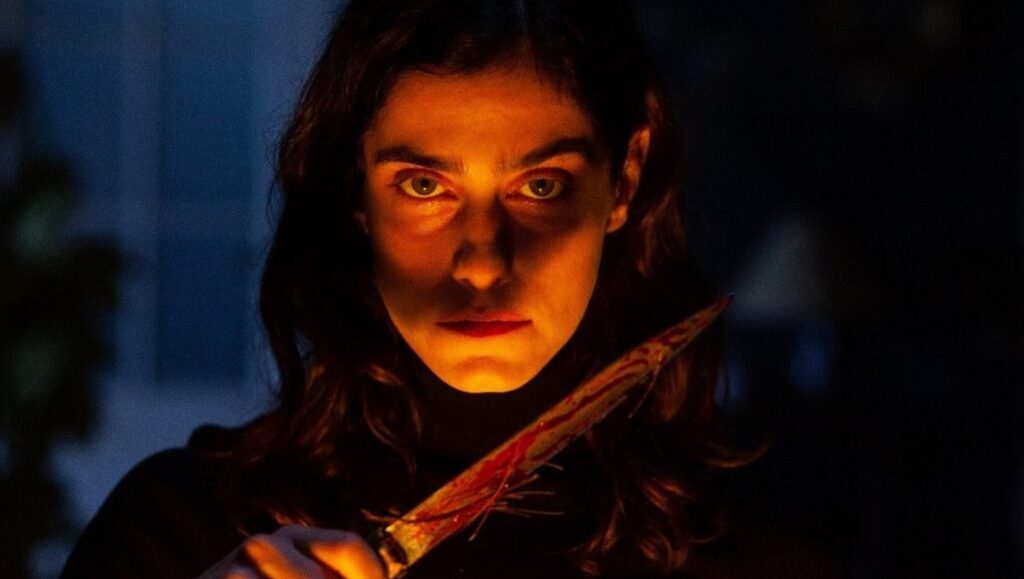 The Advent Calendar movie still. Woman holds bloody knife, horror film.