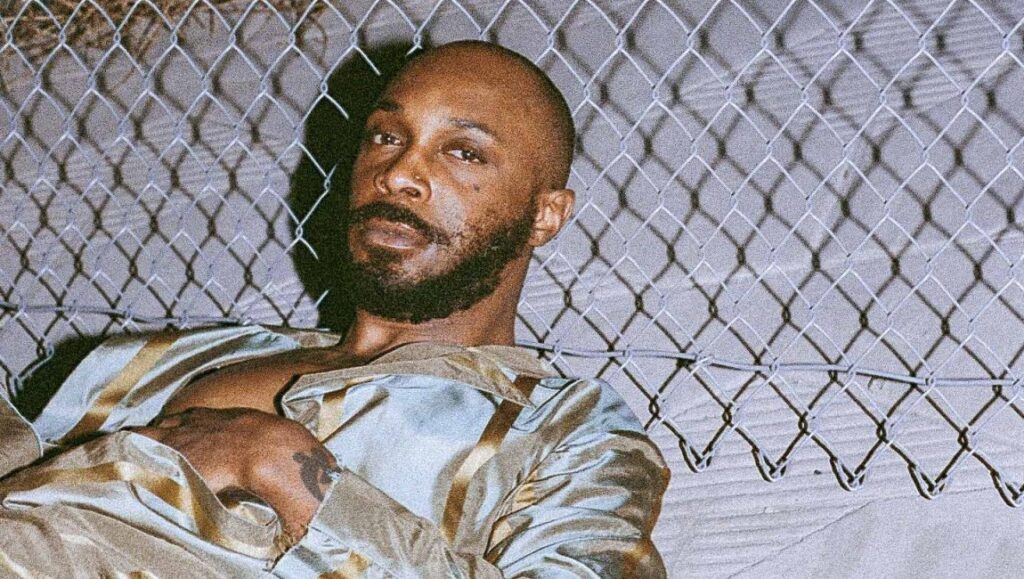 JPEGMAFIA, top album of 2021. Rapper with beard and nose ring in front of a chain link fence. Alternative hip hop artist.