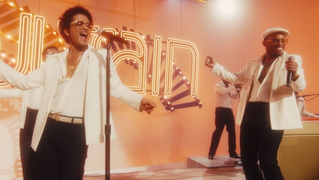 Silk Sonic | An Evening With Silk Sonic Silk Sonic performing live. Bruno Mars and Anderson .Paak on stage in white suits. November 2021 album roundup.