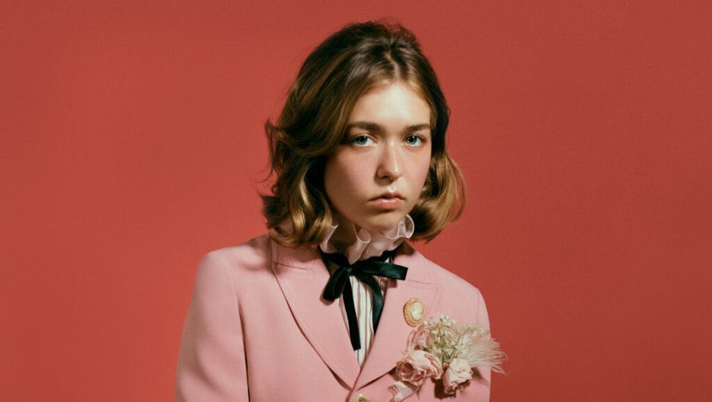 Snail Mail, Lindsey Jordan in November 2021 album roundup. Musician in pink suit with floral brooch.