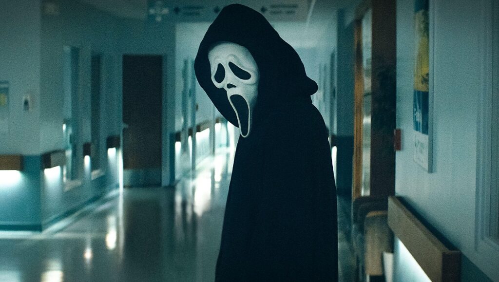 Scream — Matt Bettinelli-Olpin & Tyler Gillett Ghostface in Scream (2022) reboot. Horror movie villain wearing black robe and white mask in a hospital hallway.