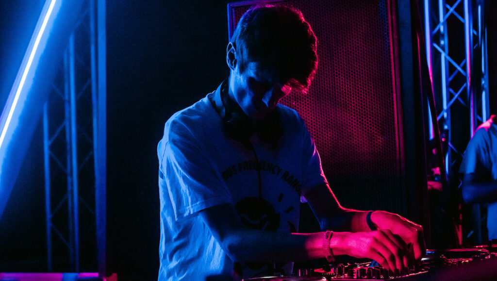 Best Albums of 2021: Skee Mask | Pool Skeemask, top album of 2021. DJ mixing music with neon lights. Best music albums.