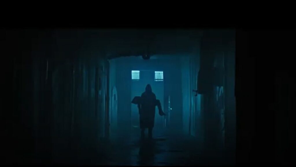 Stoker Hills movie still. Dark hallway with figure carrying a body. Horror film scene.