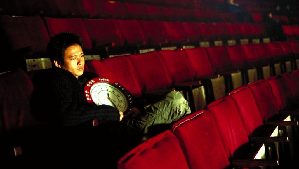 Tsai Ming-liang's What Time Is It There? film still. Man with clock in theater.