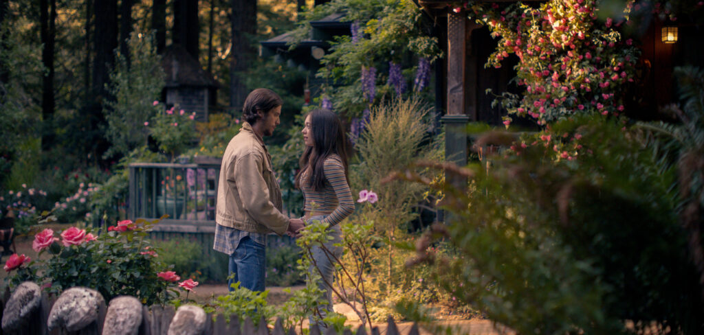 The Sky is Everywhere movie still. A man and woman hold hands in a lush garden. Josephine Decker film.