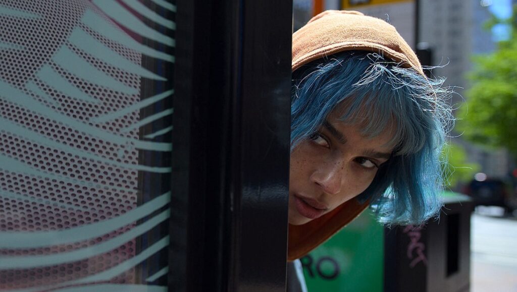 Zoë Kravitz as Kimi, Steven Soderbergh film. Woman with blue hair peers from behind a structure.