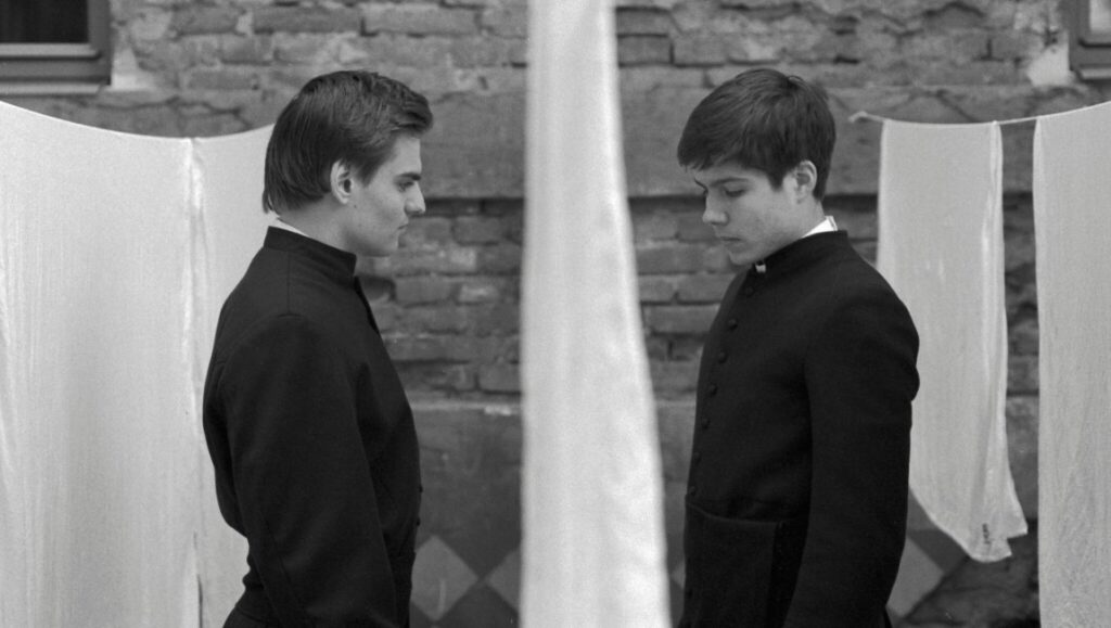 Servants — Ivan Ostrochovský Servants movie still. Two priests in black cassocks face each other in a black and white scene.
