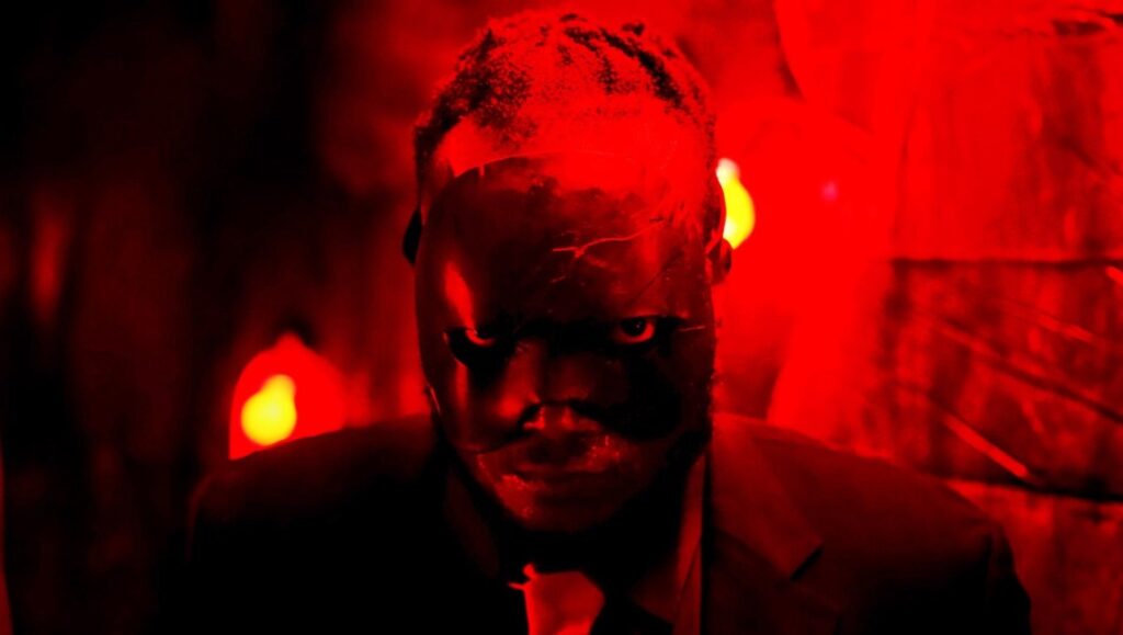 Man in suit with mask under red light. Horror, thriller, mystery concept.