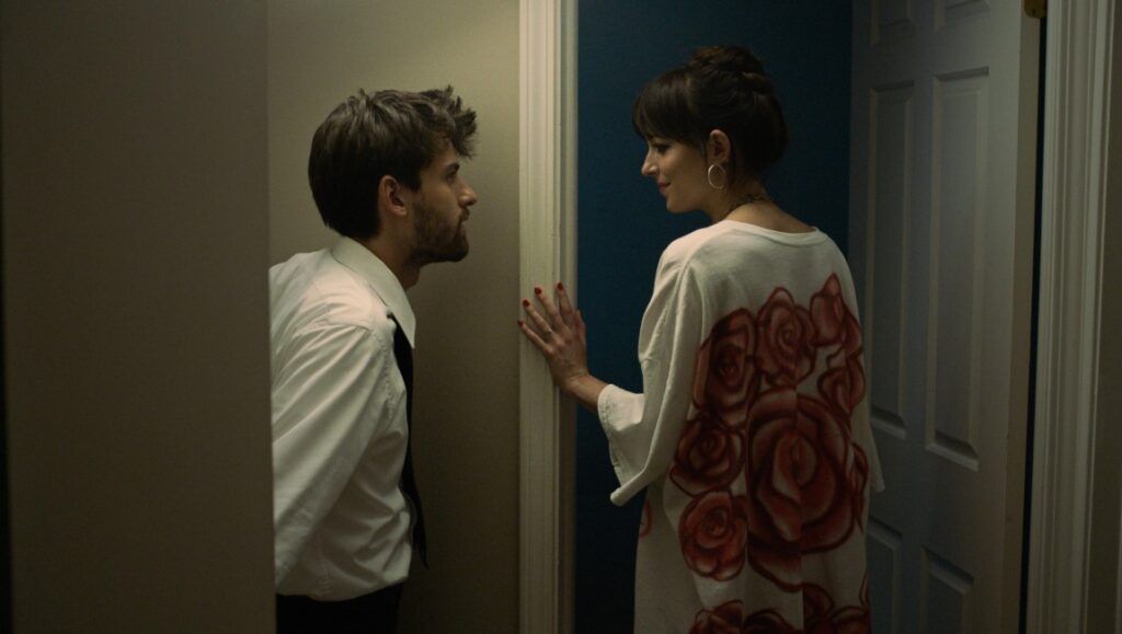 Cha Cha Real Smooth movie scene. Dakota Johnson and Cooper Raiff in a doorway. Romantic drama film.