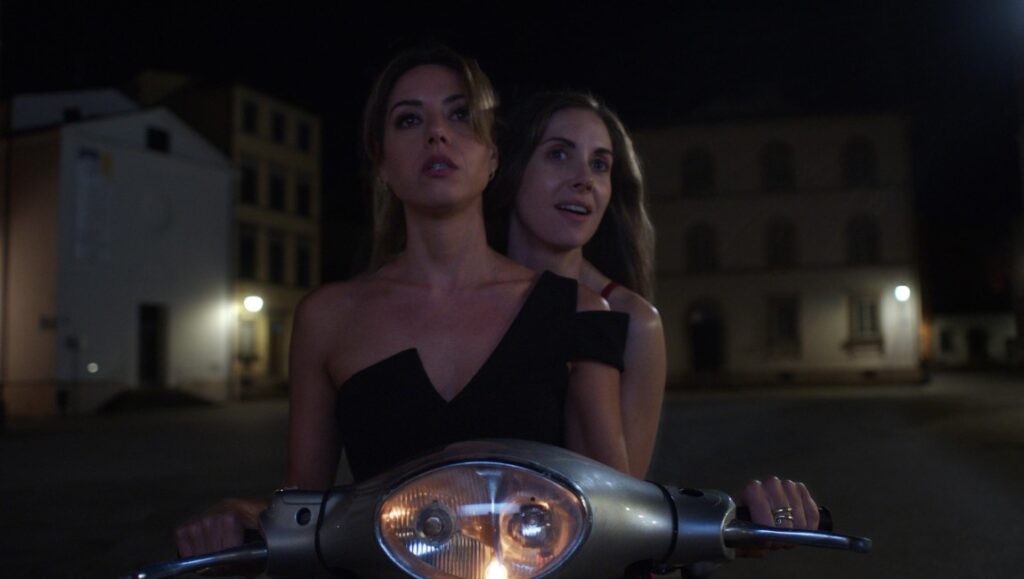 Spin Me Round — Jeff Baena Aubrey Plaza and Alison Brie on a scooter at night. Spin Me Round movie scene.