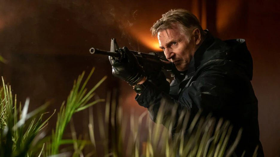 Liam Neeson in Memory movie. Armed man aiming rifle. Martin Campbell film.