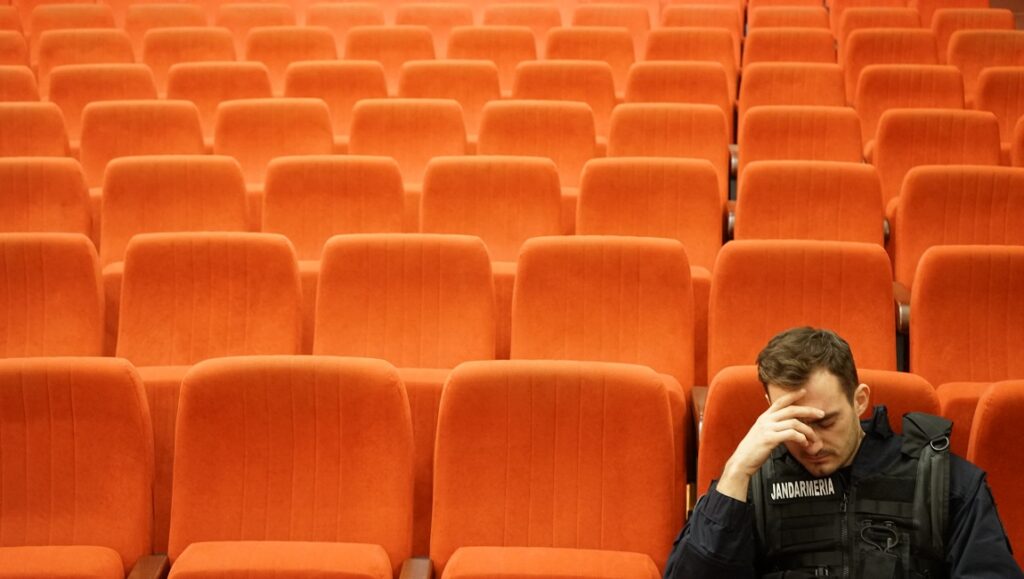 Poppy Field — Eugen Jebeleanu Poppy Field movie still. A man in uniform sits dejectedly in a theater. Empty orange seats.