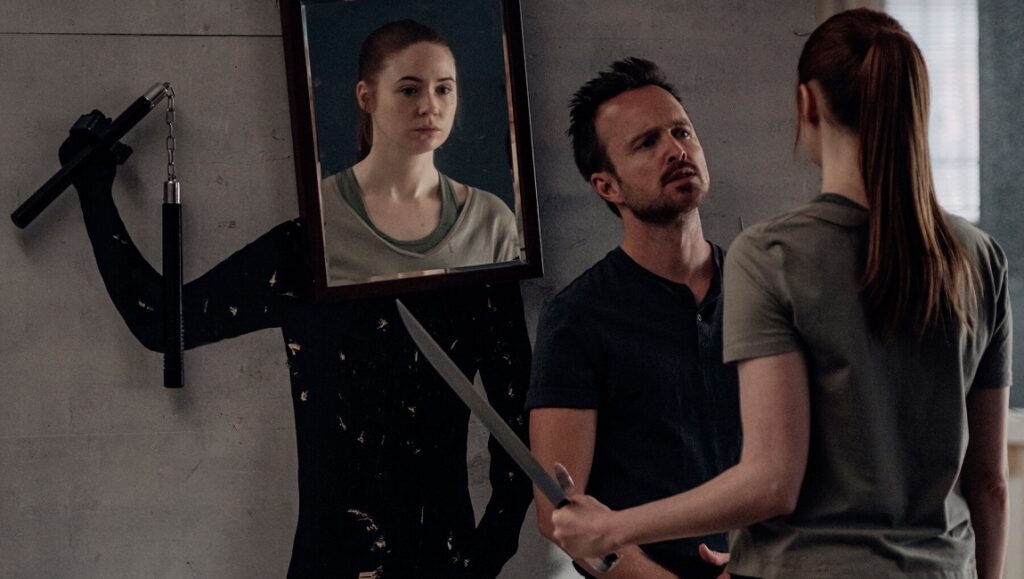 Dual — Riley Stearns Karen Gillan in Dual movie. Aaron Paul holds sword. Wall art with nunchucks and mirror. Sci-fi thriller.