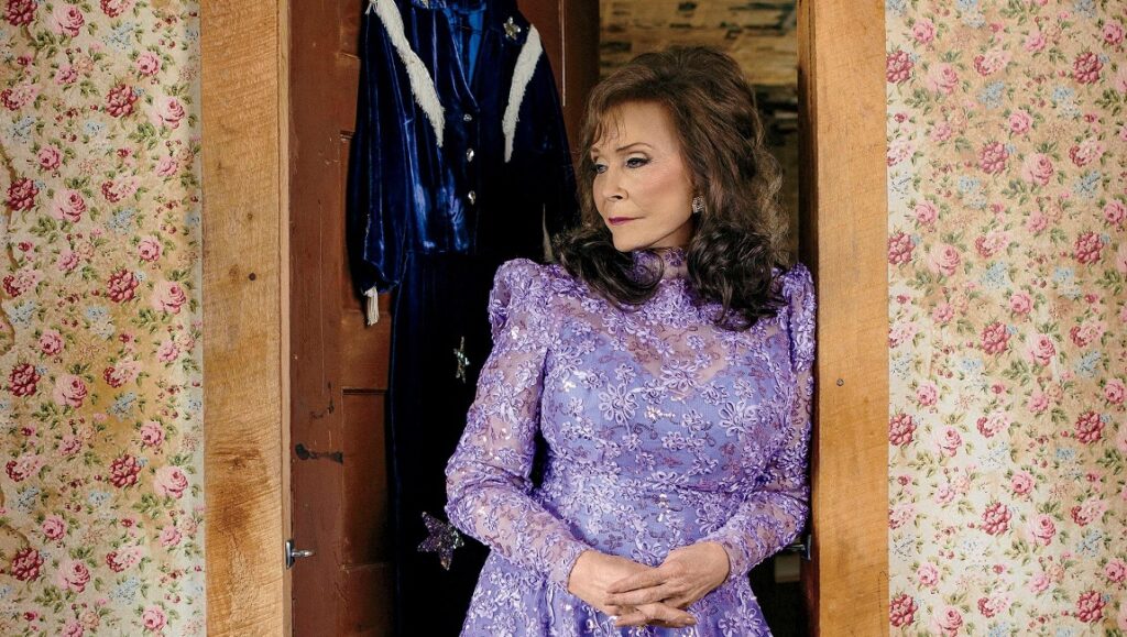 Loretta Lynn, Van Lear Rose album. Country music icon in purple lace dress with floral wallpaper.