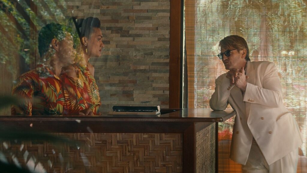 Pacifiction movie scene. Man in white suit, sunglasses. Tropical shirt, island setting. Albert Serra film.