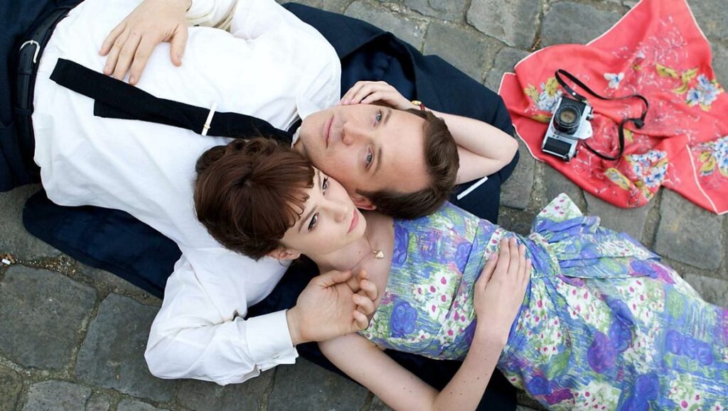 An Education — Lone Scherfig An Education movie still. Carey Mulligan and a man lie on the ground with a vintage camera and scarf.