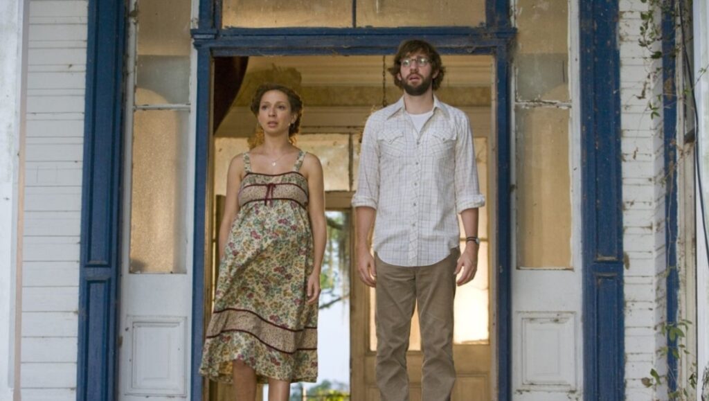 Maya Rudolph and John Krasinski in Away We Go movie. Pregnant woman and man stand in doorway.