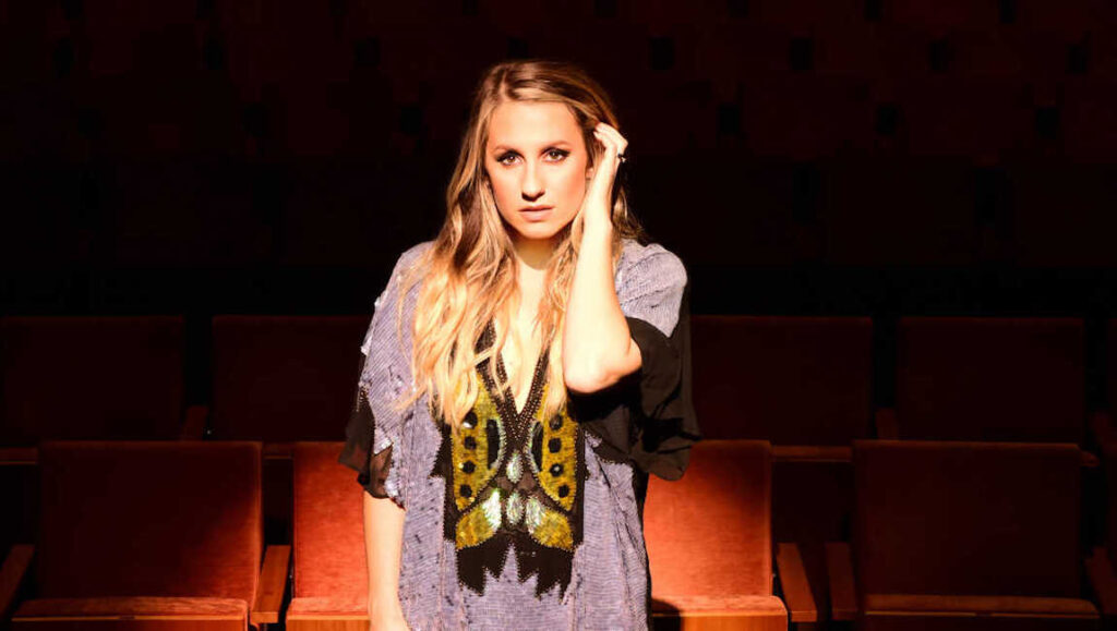 Caitlyn Smith album review. Singer in patterned top with long blonde hair. April 2022 album roundup.