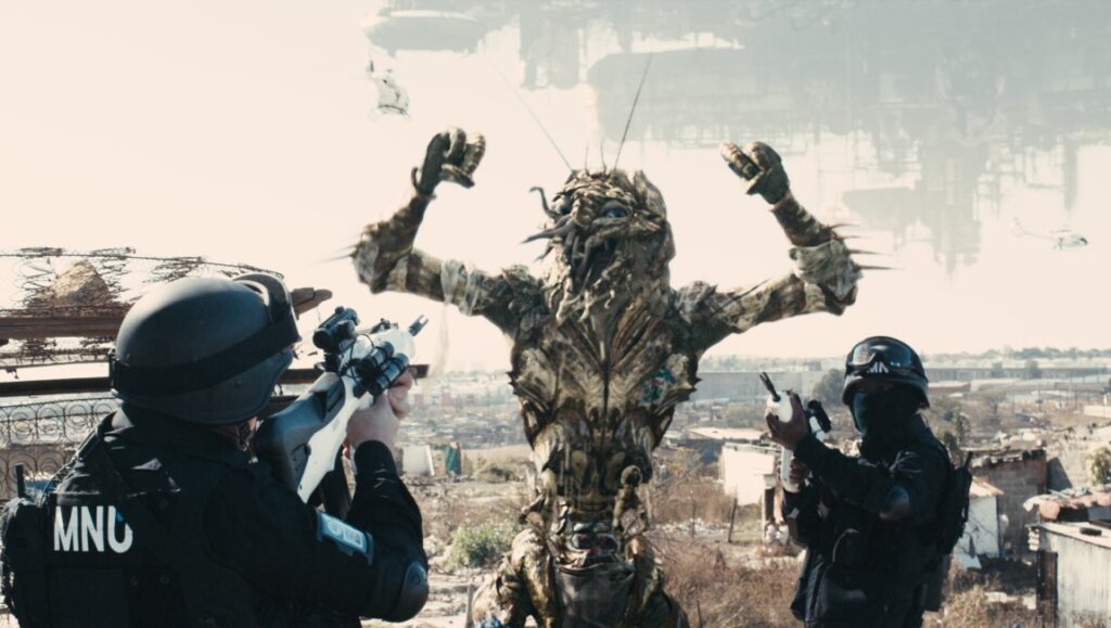 District 9 movie scene: Prawn alien with hands up, surrounded by armed MNU soldiers. Sci-fi film by Neill Blomkamp.