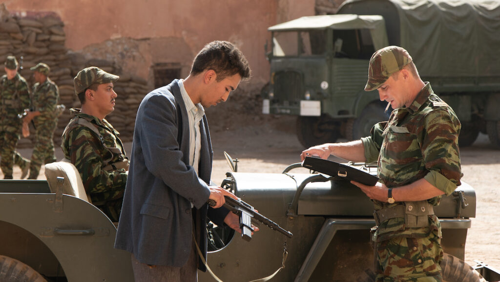 Scene from Harkis at Cannes Film Festival. Soldiers, jeep, and a man holding a rifle. Cannes 2022 film.