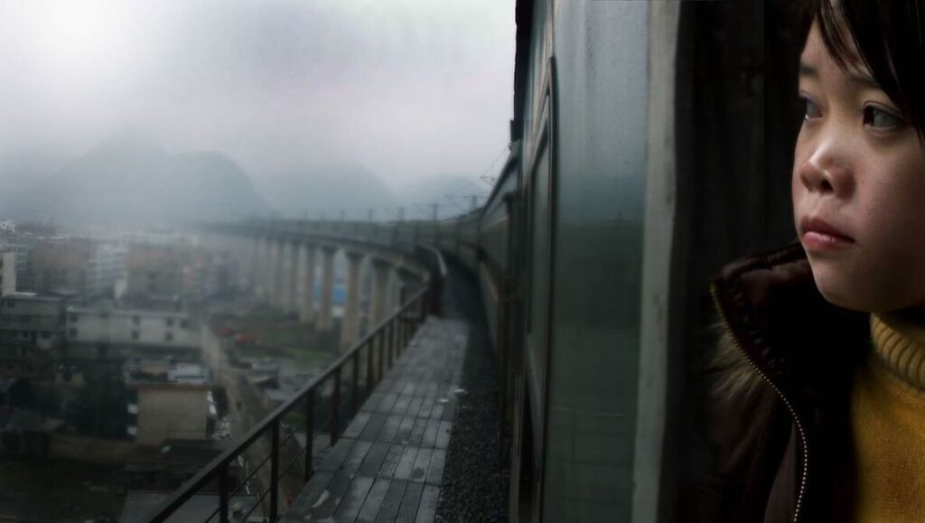 Last Train Home — Lixin Fan Pensive child on a train, gazing at a misty landscape. Travel scene with a railway bridge and town.