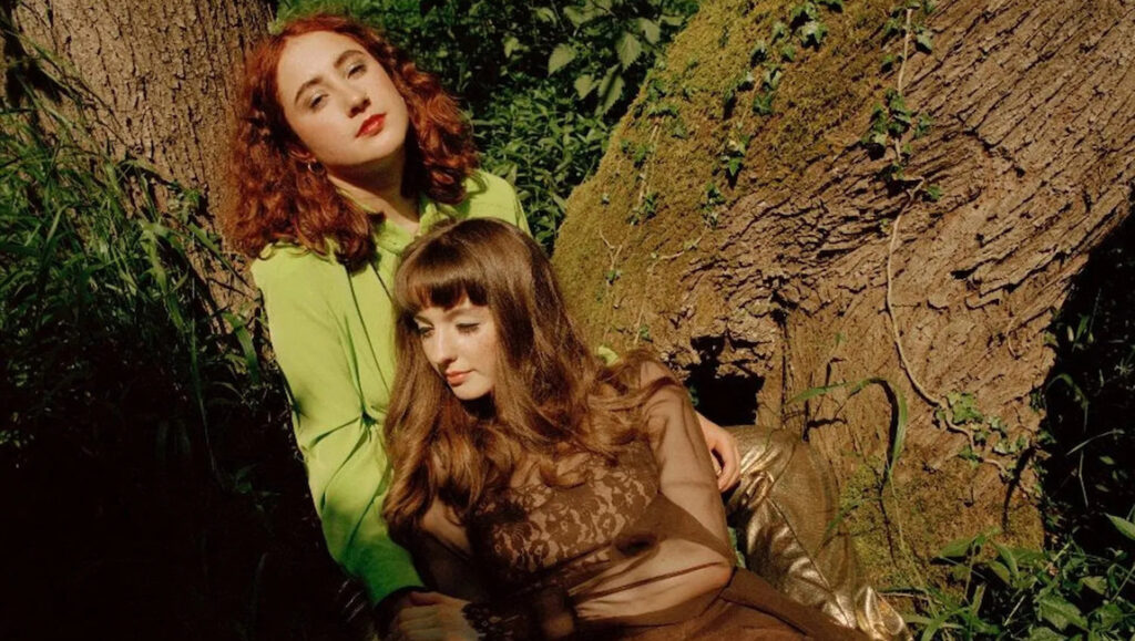 Let's Eat Grandma album. Rosa Walton and Jenny Hollingworth pose by a tree. April 2022 music roundup.