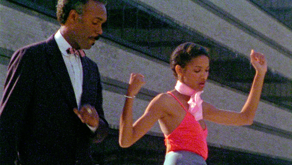 Kathleen Collins' Losing Ground film still. Man in suit, woman dancing with pink scarf.
