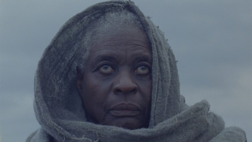 Close-up of an older woman in Magdala film by Damien Manivel. Haunting, with a gray headscarf.