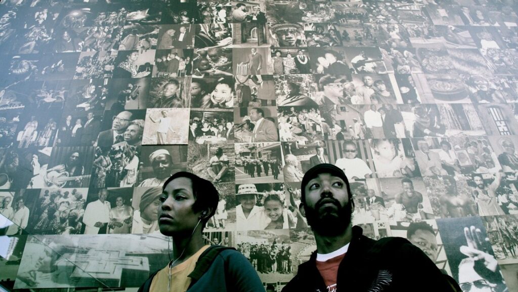Medicine for Melancholy film still. Two people stand before a wall covered in black and white photos.