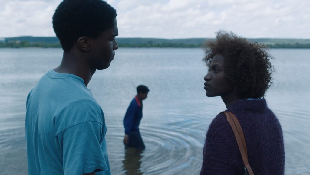 Tori and Lokita film still from Cannes Film Festival 2022. Two actors stand by a lake.