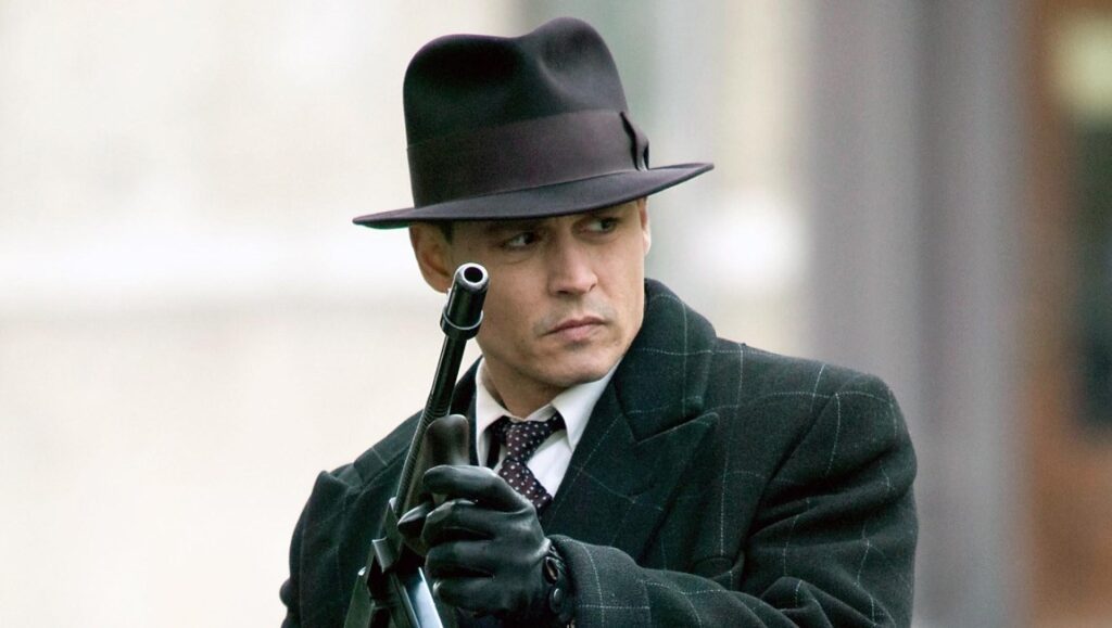 Johnny Depp as John Dillinger in Public Enemies movie. Gangster holding a gun.