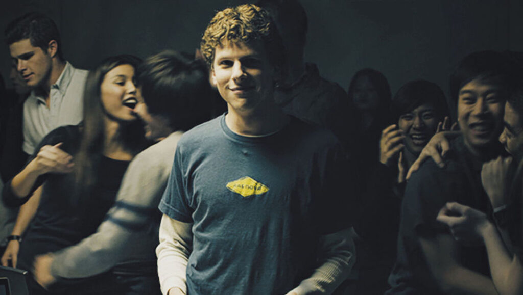 Jesse Eisenberg as Mark Zuckerberg in The Social Network movie. Group of people.