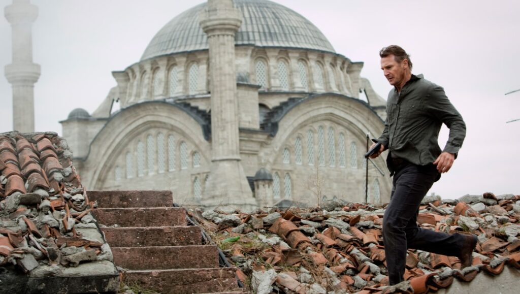 Liam Neeson in Taken movie. Action scene on a rooftop with a mosque in the background. Pierre Morel film.