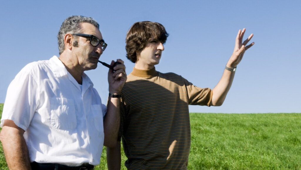 Taking Woodstock — Ang Lee Taking Woodstock movie still. Ang Lee film scene with father and son on a grassy field.