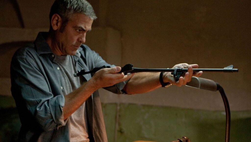The American — Anton Corbijn George Clooney aims a rifle in The American. Action movie scene with suspense.