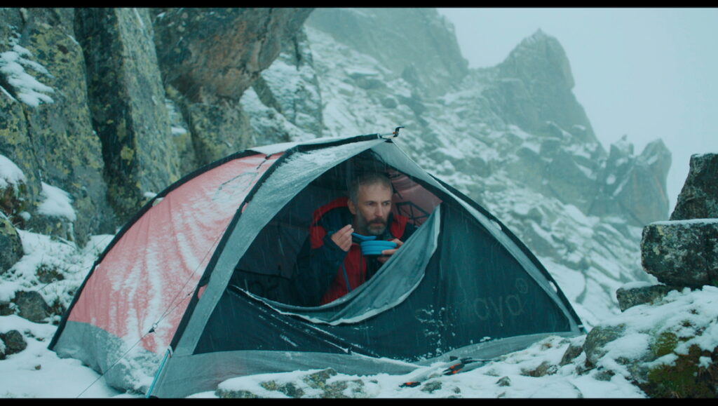 Still from The Mountain C at Cannes Film Festival. Man in tent eating in snowy mountain landscape.