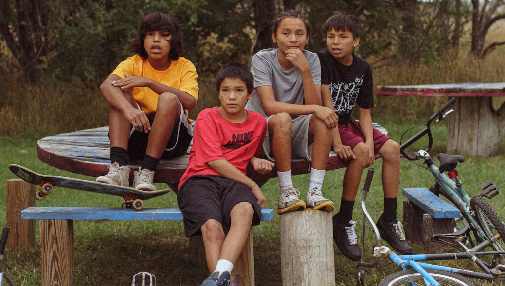 War Pony film still. Four Native American boys sit with a skateboard and bikes.