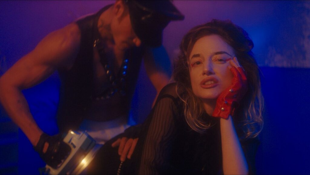 Fantasia Film Festival 2022 — Dispatch 6:Please Baby Please, Seire, Skinamarink Still from Please Baby Please at Fantasia Film Festival. Woman in red glove, man in leather.