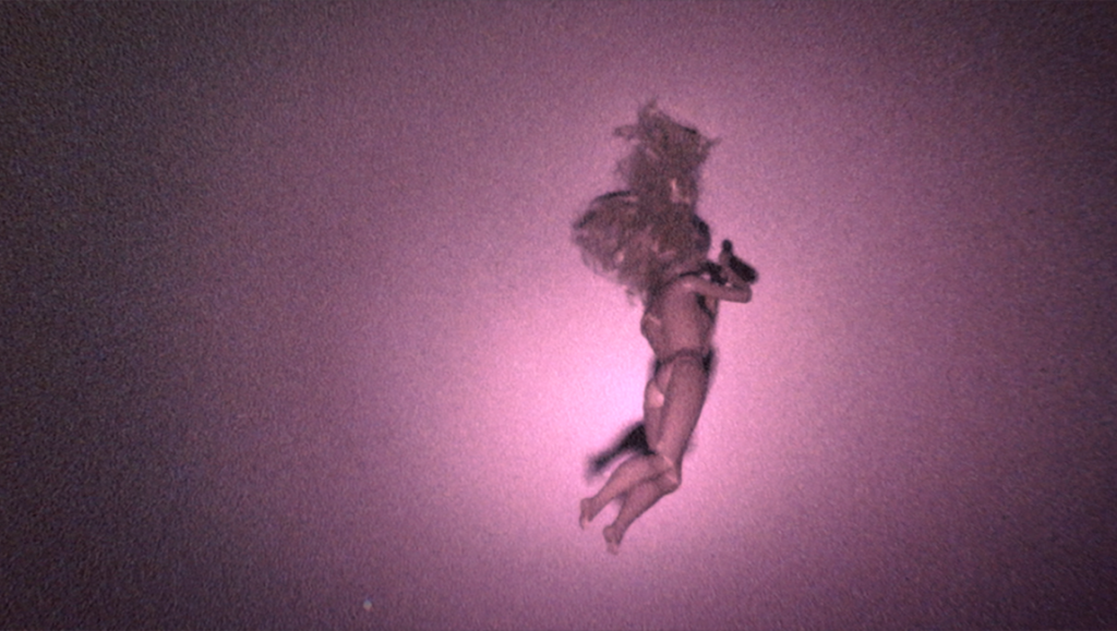 Skinamarink film still: eerie doll figure against a grainy, pink-lit background. Fantasia Film Festival 2022.
