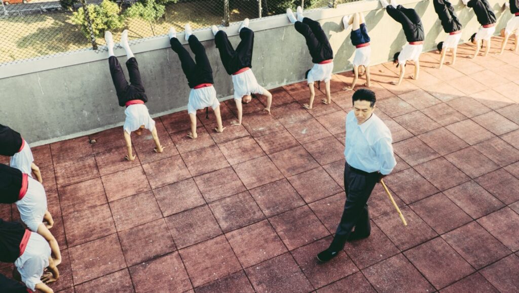 Septet: The Story of Hong Kong film still. Martial arts students perform handstands as instructor watches. SDAFF 2022.