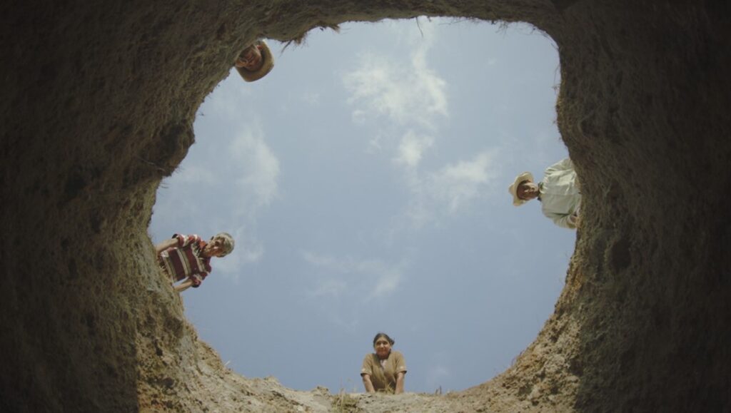 Mother Lode DOC NYC film still. People look down into a hole. Documentary about family, mining, and community.