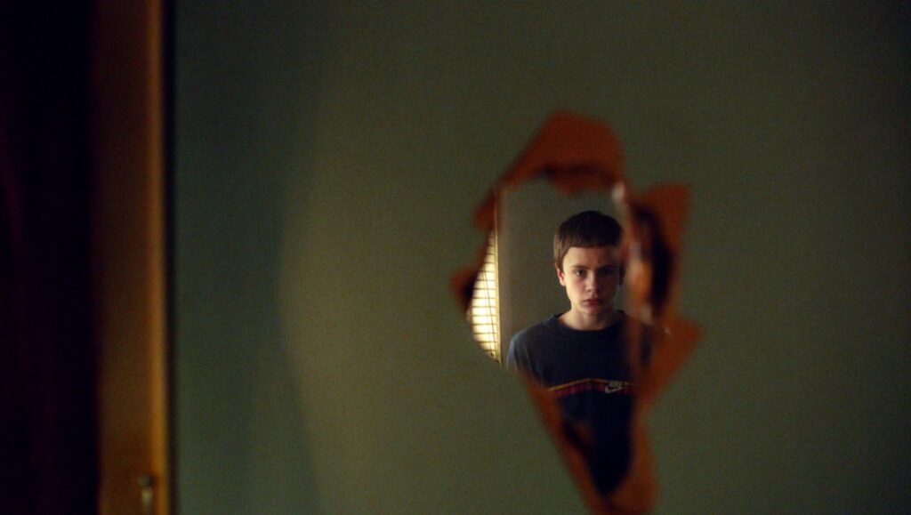Beautiful Beings film still. Boy looking through a hole in a wall. Icelandic cinema.