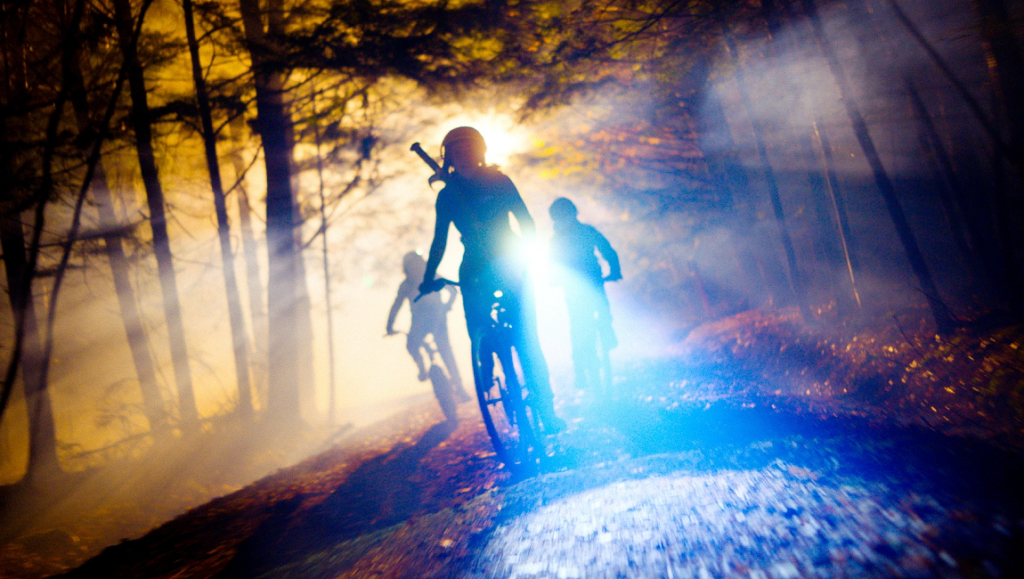 Kids vs Aliens movie scene. Children biking at night through a forest with bright lights.