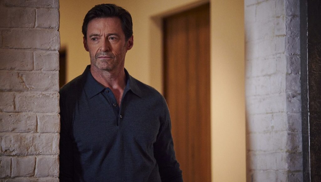 The Son — Florian Zeller Hugh Jackman in The Son movie. Actor wearing a dark polo shirt, standing near a brick wall. Drama film.