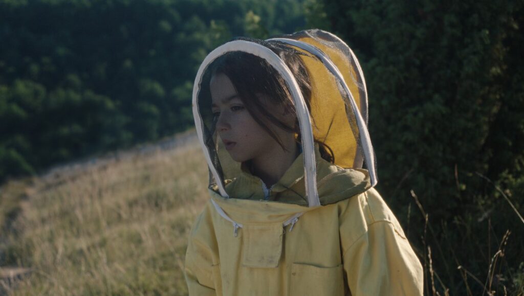20,000 Species of Bees film still from San Sebastián Film Festival 2023. Child in beekeeper suit.