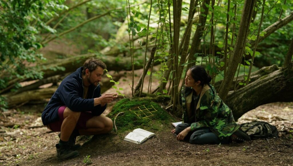 Last Summer film scene at TIFF 2023: Man and woman in forest setting with notebook.