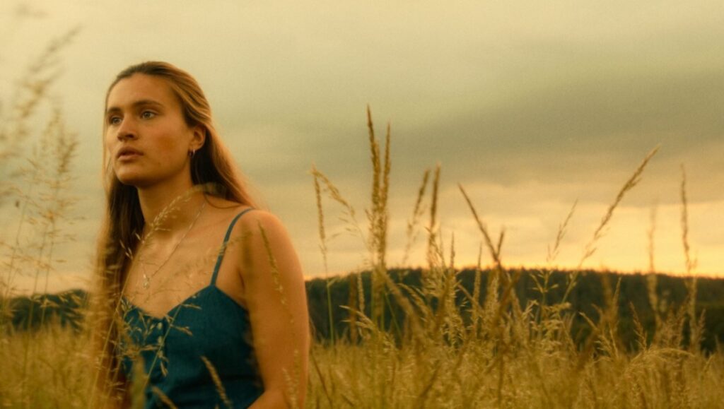 Someday We'll Tell Each Other Everything film still. Young woman in a field.